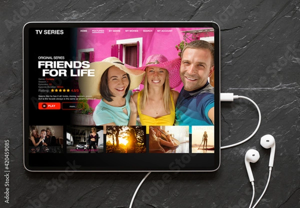 Obraz Tablet computer with earphones on black background showing movie and TV shows online streaming service app on the screen
