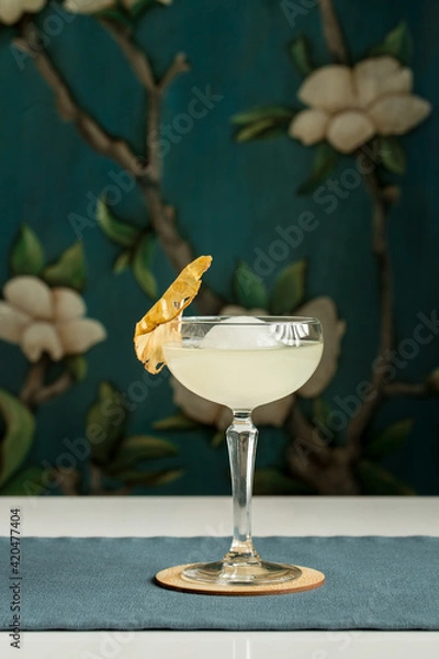 Obraz margarita glass cocktail with ice ball and dried pineapple on the table at restaurant