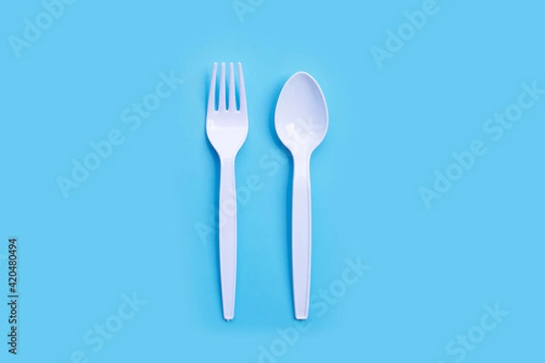 Fototapeta Plastic fork and spoon on blue background.