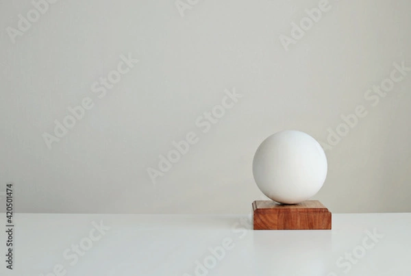 Fototapeta Stylish interior mockup with white geometric shape of a ball on a  wooden stand, copy space
