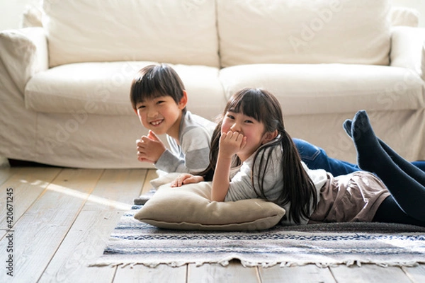 Obraz リビングの床に寝転ぶ日本人の男の子と女の子
