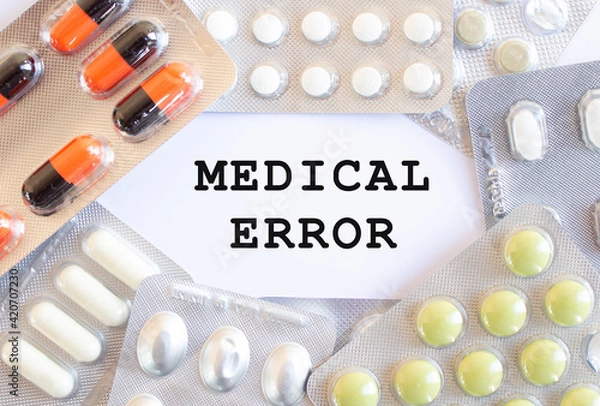 Fototapeta Text MEDICAL ERROR on a white background. There are different medicines around.