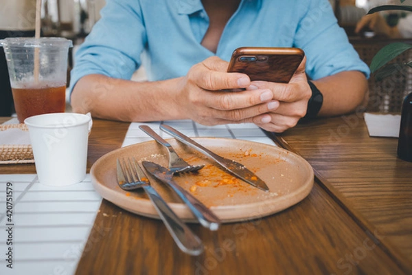 Fototapeta closeup man hand using smartphone after meal