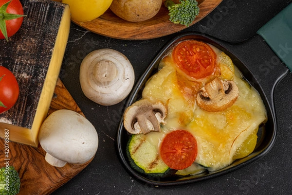 Obraz Delicious traditional Swiss melted raclette cheese on chopped boiled potatoes