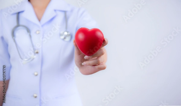 Fototapeta   Selective focus of red heart held by female nurse's hand representing giving effort high quality service mind to patient. Professional, Specialist in uniform on white background