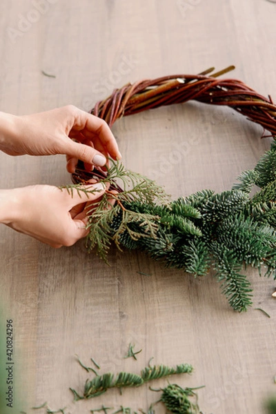 Fototapeta Creating a Christmas wreath of spruce branches, balls and stars. Decoration for the house for Christmas. Concept of florist's work before christmas holidays.