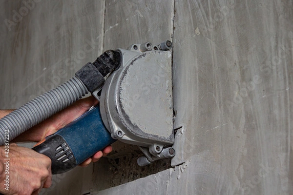 Obraz cutting a wall with a power tool at a construction site using a vacuum cleaner
