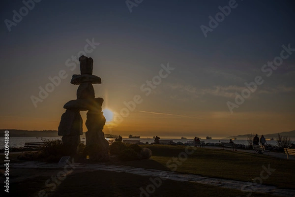 Obraz 石を積み上げて作られるカナダのイヌクシュク像に反射する夕焼け
