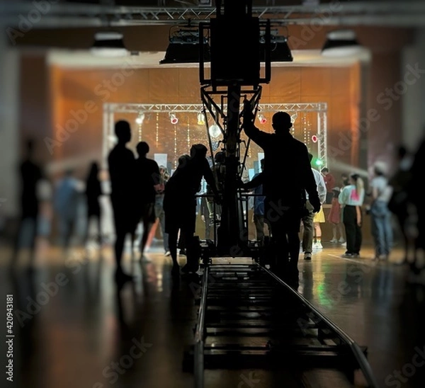 Obraz Blurred behind the scenes of music video shooting production crew team silhouette and camera equipment in studio. Soft focus. 