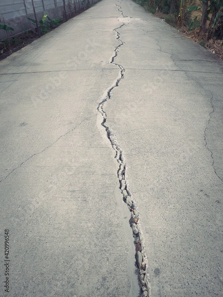 Fototapeta The cement road cracked in a long line.The collapse of the road has caused large cracks in the floor.The concrete road has large fissures.