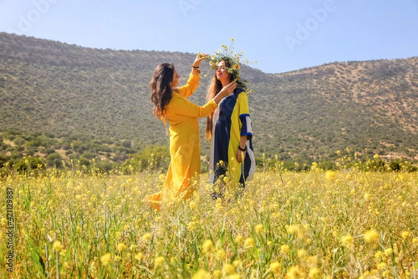 Fototapeta Two women with wreath in a field.