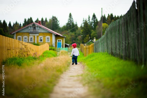 Fototapeta a little boy walks through the village, selective focus