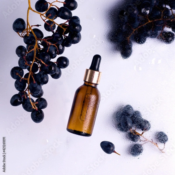 Obraz Cosmetics with grapes. Glass bottle with oil next to ripe grapes