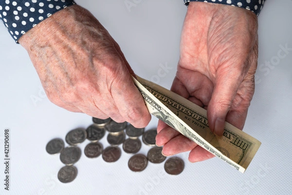 Fototapeta Close-up of an elderly woman's hand counting money on a white background. Retirement savings, home finance