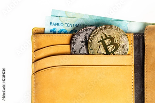 Obraz Carteira de couro com criptomoedas Bitcoin e cédulas de dinheiro isolada em fundo branco. Notas de cem Reais.
