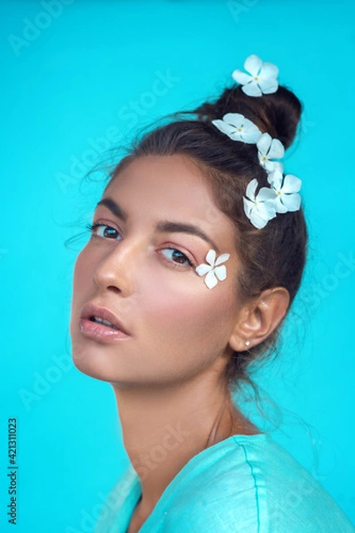 Obraz portrait of a beautiful, cute girl on a turquoise bright background with white flowers