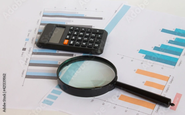 Fototapeta Calculator with magnifying glass on the diagrams