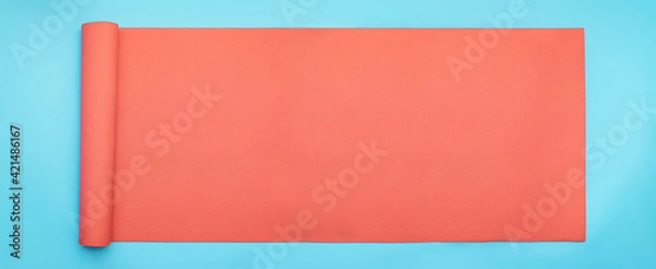 Fototapeta Minimal exercise and concept with pink fitness yoga mat on blue background. Horizontal banner size flat lay.