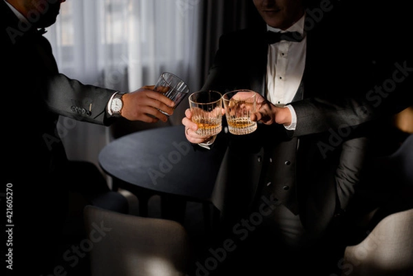 Obraz Front view of men dressed in business costumes drinking whiskey. Concept of luxury lifestyle.