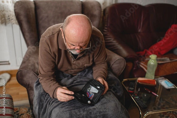 Fototapeta Senior men with glucometer checking blood sugar level at home