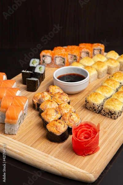 Obraz Big sushi set on light wooden dish isolated on black background
