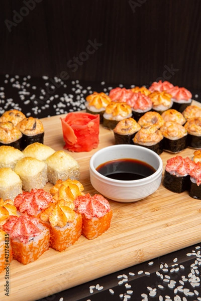 Obraz Big sushi set on light wooden dish isolated on black background
