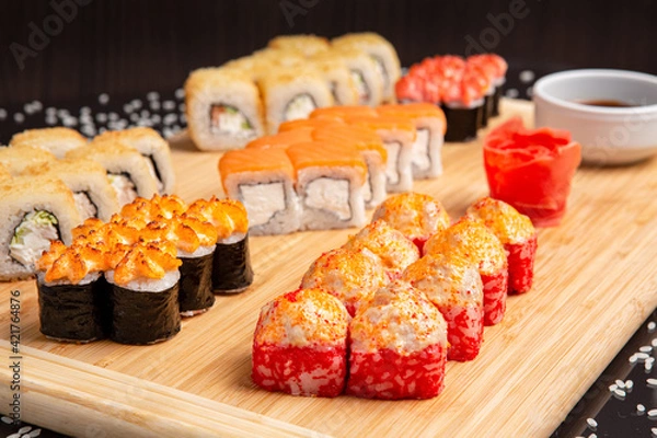 Obraz Big sushi set on light wooden dish isolated on black background