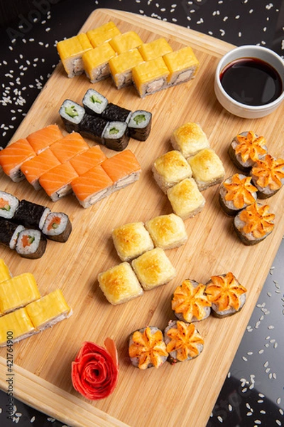 Obraz Big sushi set on light wooden dish isolated on black background
