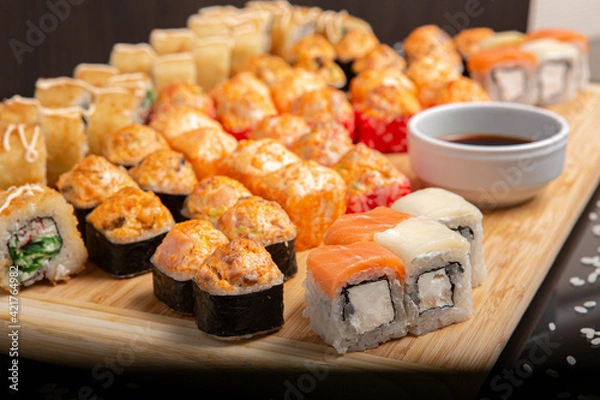 Obraz Big sushi set on light wooden dish isolated on black background