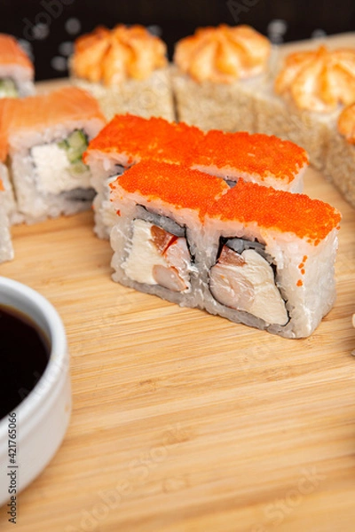 Obraz Big sushi set on light wooden dish isolated on black background