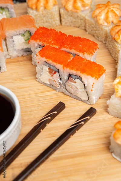 Obraz Big sushi set on light wooden dish isolated on black background