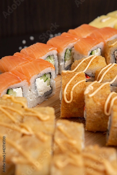 Obraz Big sushi set on light wooden dish isolated on black background