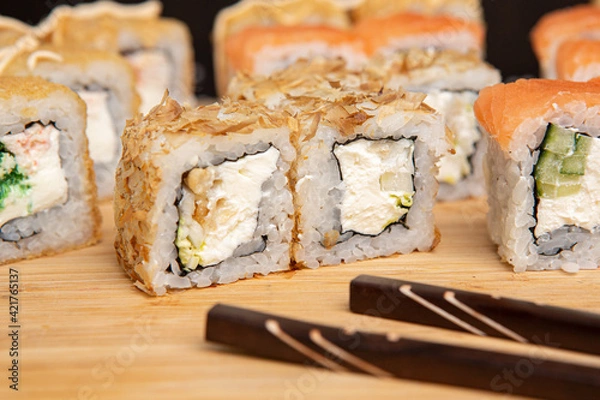 Obraz Big sushi set on light wooden dish isolated on black background