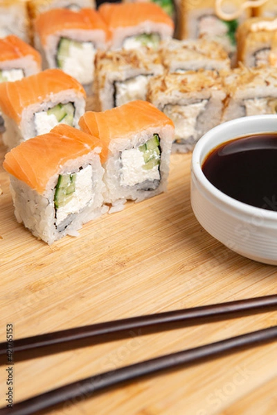 Obraz Big sushi set on light wooden dish isolated on black background