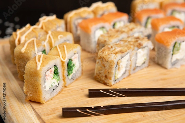 Obraz Big sushi set on light wooden dish isolated on black background