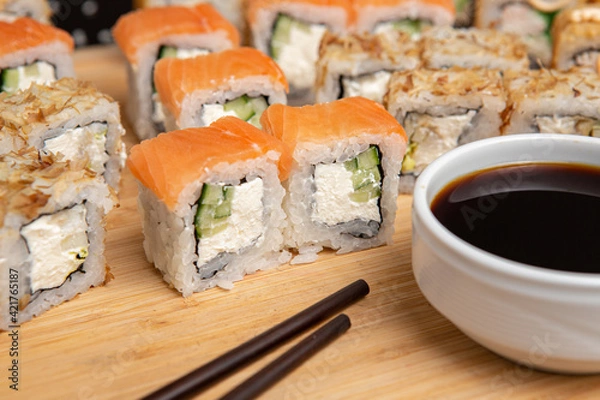 Obraz Big sushi set on light wooden dish isolated on black background