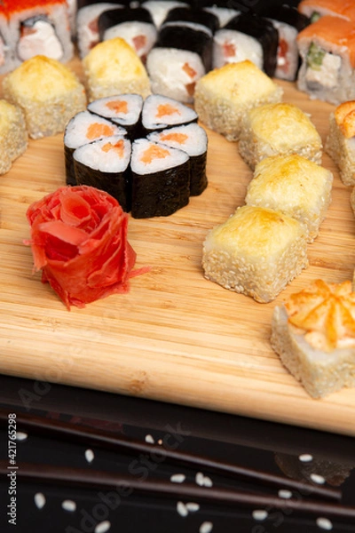 Obraz Big sushi set on light wooden dish isolated on black background