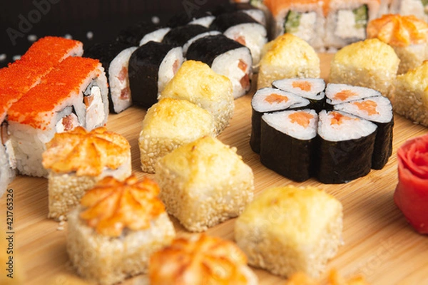 Obraz Big sushi set on light wooden dish isolated on black background