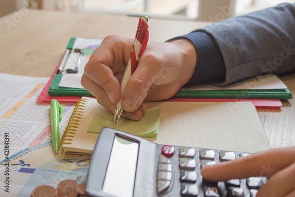 Fototapeta savings, finances, economy and home concept - close up of man with calculator counting money and making notes