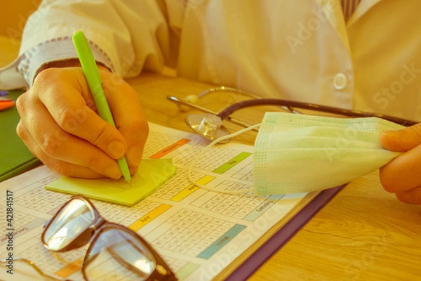 Fototapeta Physician working with paper in hospital office. Therapeutist sitting at working table making some paperwork