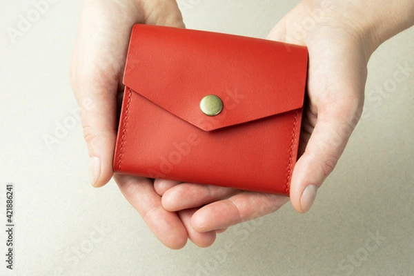 Fototapeta red leather wallet in open female hands close-up on gray background with shadows