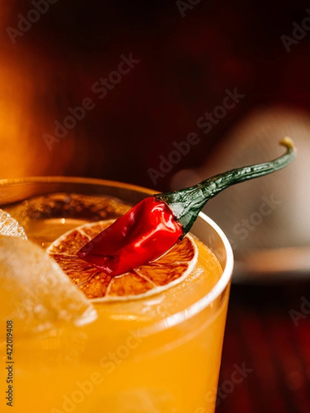 Obraz orange cocktail with a slice of orange and hot red pepper. On a wooden table