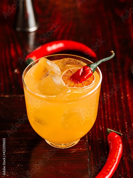 Obraz orange cocktail with a slice of orange and hot red pepper. On a wooden table