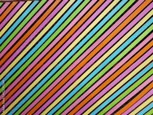 Obraz Diagonales parallèles et colorées selon une alternance passant du violet, au jaune, au bleu, au vert, au violet, à l'orange. Chaque bande de couleur es séparée de la suivante par une bande noire plus 