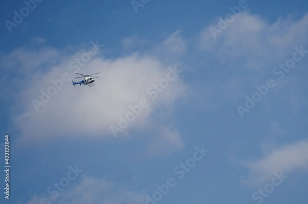 Fototapeta Helicopter against a bluaerial, propeller, power, speed, white, copter, technology, machine, high, clouds, sky, helicopter, blue, fly, air, chopper, flight, landing, plane, travel, ae sky with clouds.