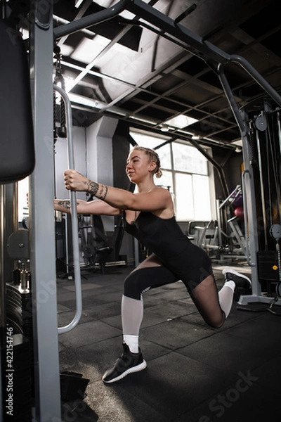 Fototapeta Vertical shot of a sportswoman doing glutes exercise at the gym