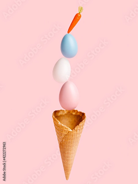 Fototapeta Ice cream cone with painted eggs and carrot on the top against pastel pink background. Minimal Easter concept. Abstract summer sweet food idea.
