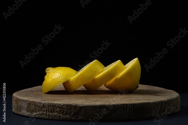 Fototapeta Lemon on a dark background. Sliced lemon on a black background. Creative photo of lemon.