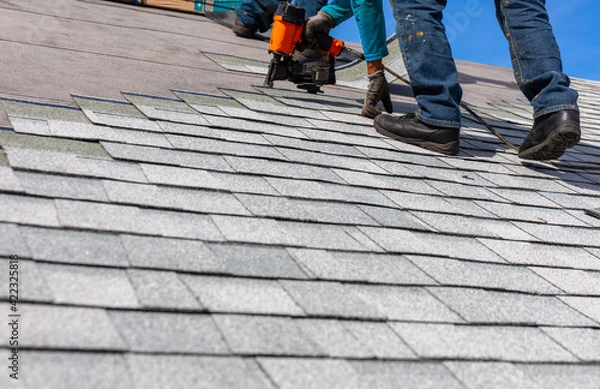 Obraz roofer installing roof shingles with nail gun