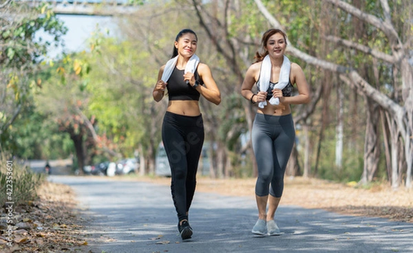 Fototapeta Happy young asian women in sportswear jogging and running outdoor. Lifestyle healthcare concept
